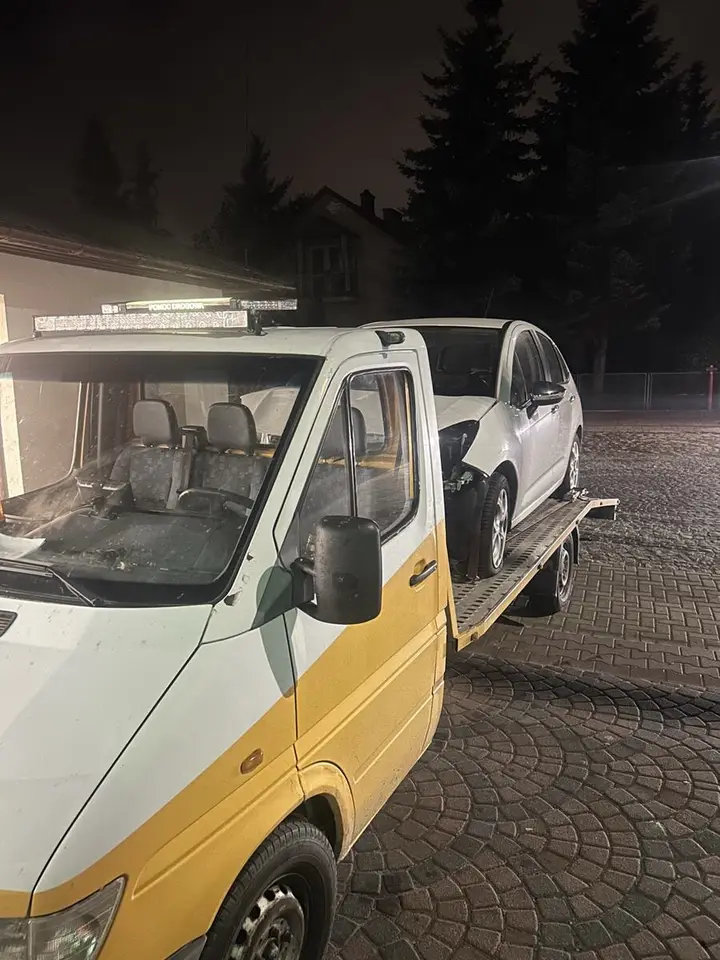 Laweta nocą z włączoną belką świateł. Na belce widać napis pomoc drogowa.